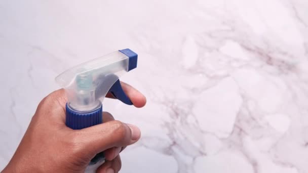 Mão segurando pano de limpeza de microfibra azul e frasco de spray — Vídeo de Stock