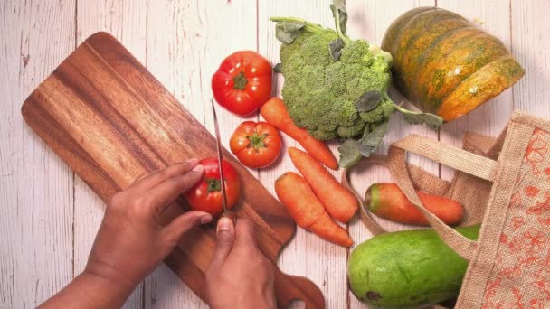 Bovenaanzicht van handgesneden tomaat met mes op snijplank — Stockvideo