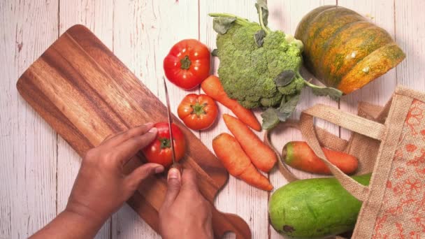 Vista superior del hombre corte a mano de tomate con cuchillo en la tabla de cortar — Vídeo de stock