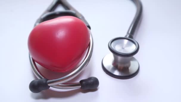 Stetoscopio e cuore su sfondo bianco, vista dall'alto — Video Stock