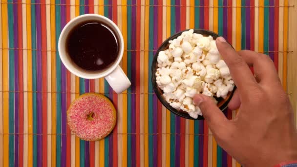 Close up de pipoca em uma tigela com chá e donut na mesa — Vídeo de Stock