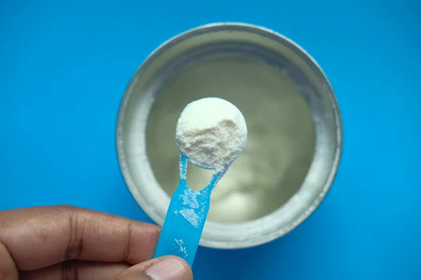 Açık arkaplanda süt tozu ve mavi kaşık