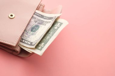 Pembe cüzdan ve pembe arka planda Amerikan doları banknotları. .