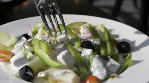 Färsk grekisk sallad - fetaost, tomat, sallad, svarta oliver och lök. — Stockvideo