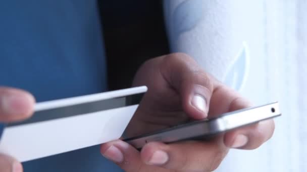 Mans online alışveriş için akıllı telefon kullanarak kredi kartı tutuyor — Stok video
