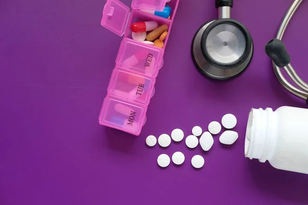 Behållare, stetoskop och piller box på lila bakgrund — Stockfoto