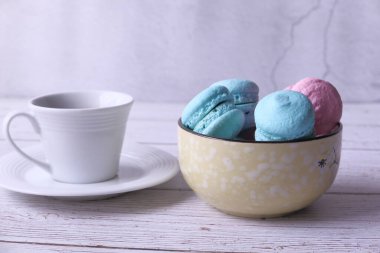 Bir kasede mavi ve pembe renkte badem kurabiyesi yakın. 