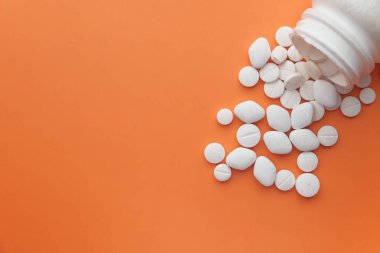 Pembe arka planda konteynırdan dökülen renk hapları, üst görünüm