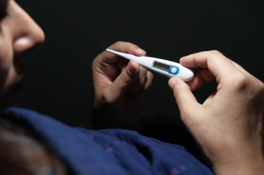 Hasta kadın sıcaklığı evdeki termometreyle ölçüyor..