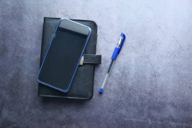 akıllı telefon, not defteri ve kalemi olan düz bir çalışma masası .