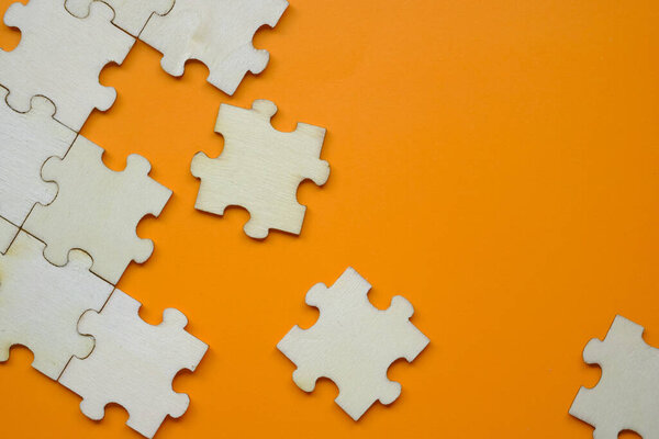 Pieces of puzzle on orange background, close up.