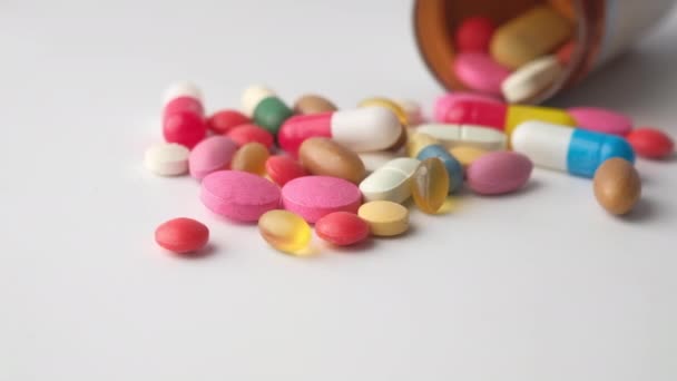 Kleur pillen morsen uit container op geïsoleerd op wit — Stockvideo