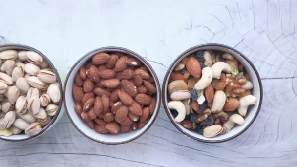 Mixed nuts in wooden bowls on table, top view — Stock Video