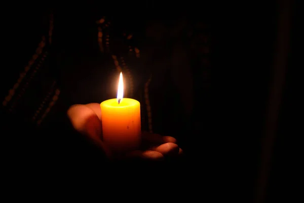 Mano de las mujeres sosteniendo una vela encendida en la oscuridad —  Fotos de Stock