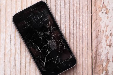 Ahşap masadaki kırık akıllı telefonu kapat. .