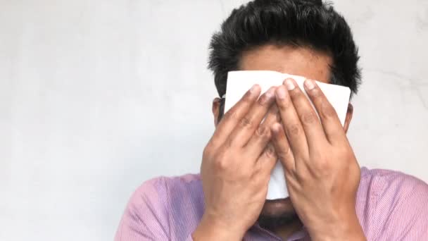 У больного молодого человека аллергия на грипп чихает в носовой платок, сморкаясь. — стоковое видео