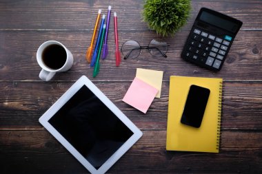 Tahta masadaki dijital tablet, kalem ve çayın üst görüntüsü 