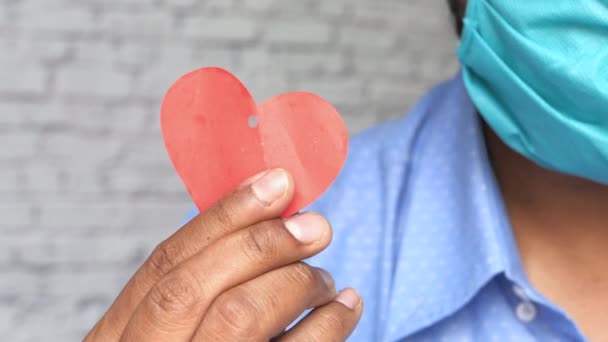 Een man met een masker met een hartvorm voor hoop en liefde — Stockvideo