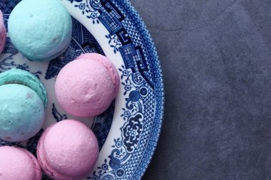 Bir kasede mavi ve pembe renkte badem kurabiyesi yakın. 