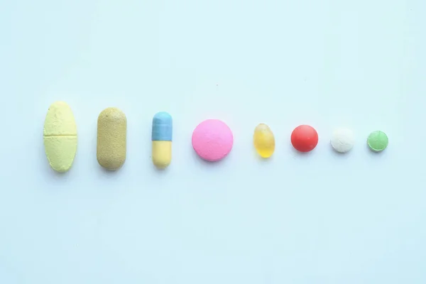 Drogues et capsules dans une rangée sur fond blanc — Photo