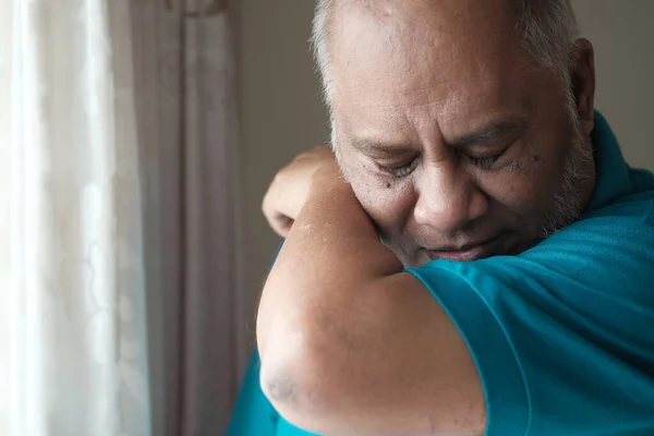 Senior man coughs or sneezes while covering mouth with elbow . — Stock Photo, Image