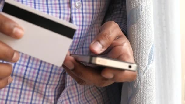 Mans mãos segurando um cartão de crédito usando telefone inteligente para compras on-line — Vídeo de Stock