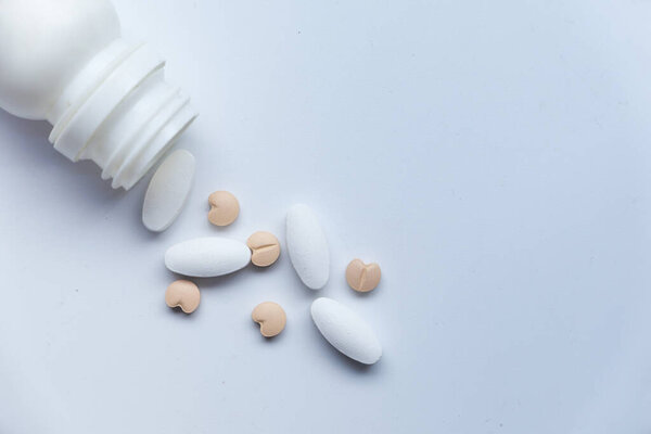 white pills spilling from container, top view 
