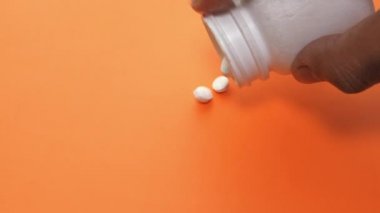 uyuşturucu ve kapsül renk arkaplanına konteynırdan dökülüyor 