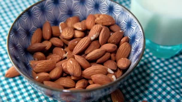Close up of almond nut in a bowl and milk on table — Stock Video