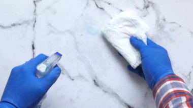 Mavi lastik eldiven, temizleme bezi ve sprey şişesi..