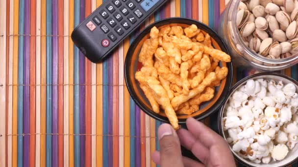 En skål med popcorn chips, nötter och TV-fjärrkontroll, — Stockvideo