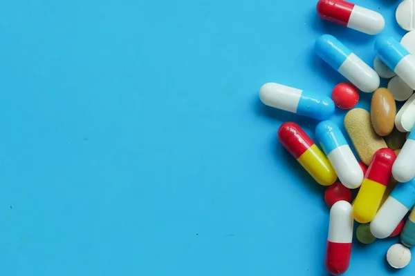 Färgglada piller och kapsel på blått med kopieringsutrymme — Stockfoto