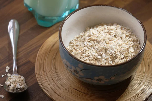 Rolled oats or oat flakes in wooden bowl on table — Stock Photo, Image