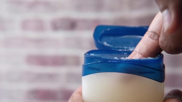 Man hand use white petroleum jelly on blue background — Stock Video