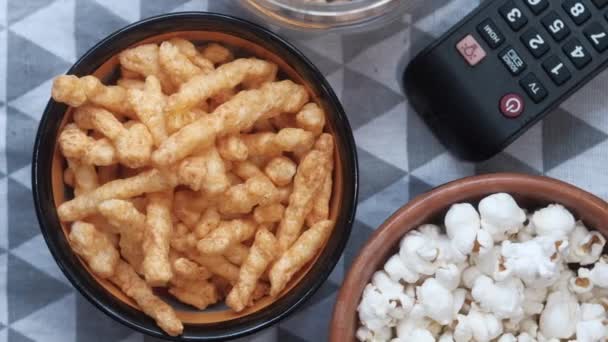 Mísa s popcorn chipsy, ořechy a TV dálkové, — Stock video