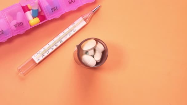 Vista superior de pílulas brancas, termômetro e caixa de pílula — Vídeo de Stock