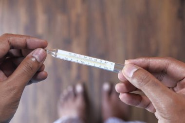 Adamın eli termometrede, sıcaklık bir termometreyle ölçülüyor.