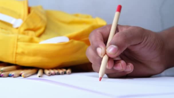 Little boy draws with pencils on white paper on table — Stock Video