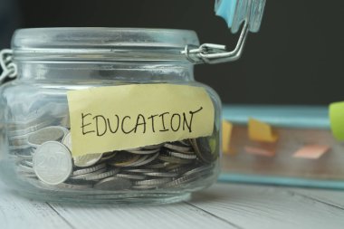 Eğitim etiketli cam kavanozdaki sikkeler.