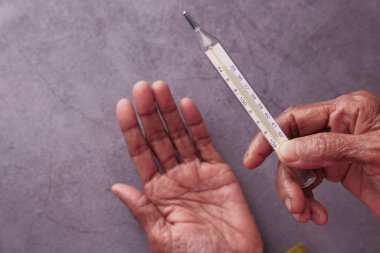 Hasta kıdemli kadın termometreyi tutuyor. .