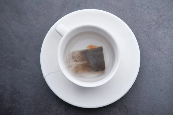 Zbliżenie torebki herbaty i filiżanki herbaty na stole. — Zdjęcie stockowe