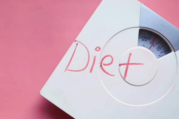 Dieet woord op gewicht machine op roze achtergrond. — Stockfoto