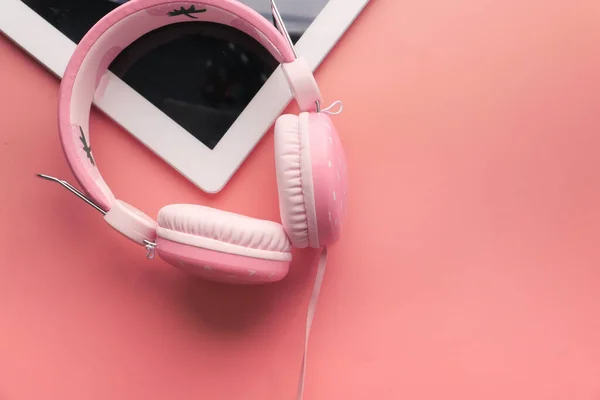 Écouteurs et tablette numérique sur fond rose . — Photo