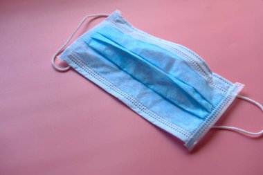 Pembe arka planda tıbbi maske, Corona koruması.