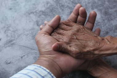 Young man holding hands with a senior lady.