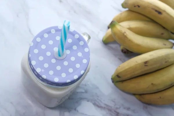 banana milkshake and banana on table, top view