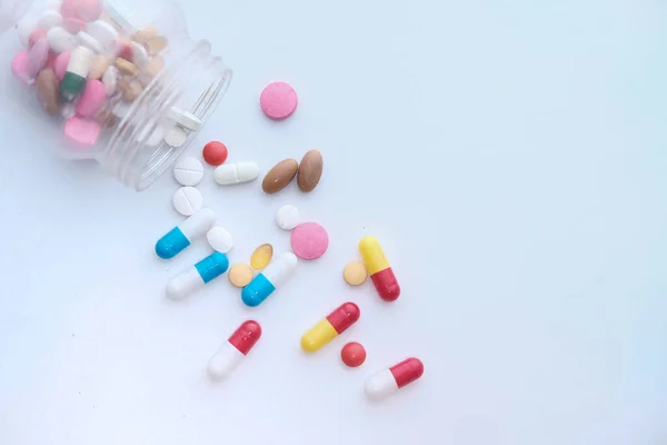 Pills spilling from a container on white background — Stock Photo, Image