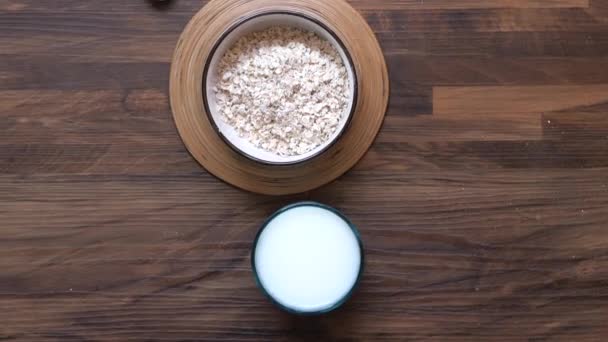 Vista de ángulo alto de copos de avena y leche sobre la mesa — Vídeos de Stock