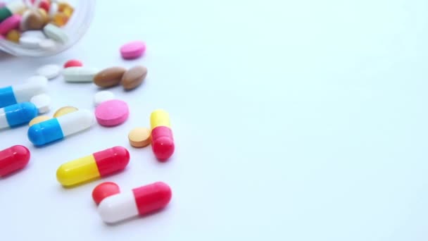 Pills spilling from a container on white background — Stock Video