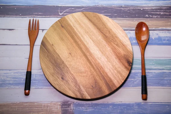 Tábua de corte com garfo de madeira e colher em mesa de madeira . — Fotografia de Stock